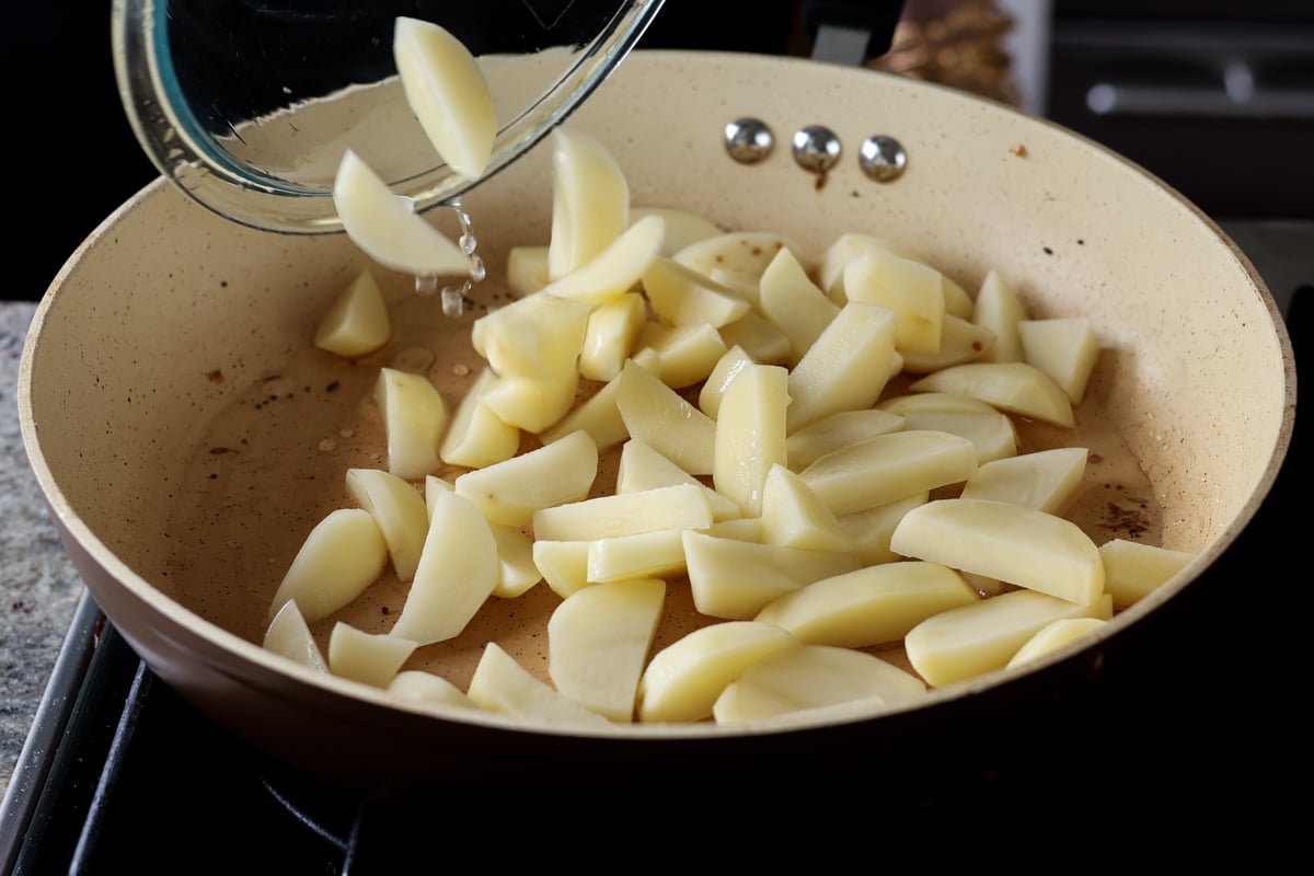 adding potatoes to the pan