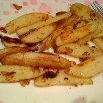 Close up of baked garlic cajun fries on a white plate, a fork in the background