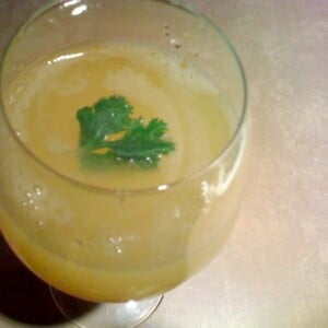 A top down shot of Aam Panna in a glass, garnished with a green herb