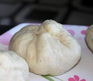A closeup of a veggie bao on a white and pink patterned plate