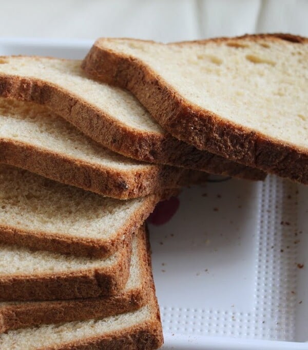 A pear carrot and oats bread loaf sliced on top of a white plate