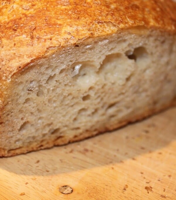 No knead bread sliced in half on a wooden work surface