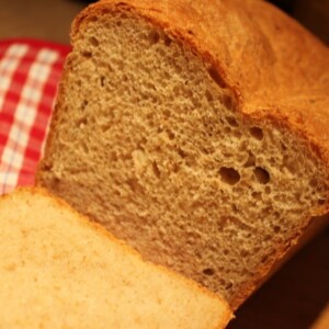 A potato bread loaf cut into slices on a red and white cloth
