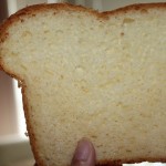 A slice of white sandwhich loaf being held towards the camera