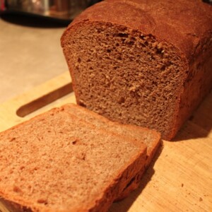 A loaf of chocolate bread with the end sliced off, on a wooden chopping board