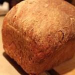 A loaf of Blueberry Apple Wheat Bread on a wooden chopping board