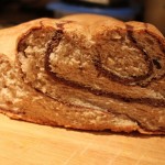 A loaf of chocolate swirl bread cut in half on a work surface