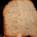 A slice of an orange blueberry multigrain loaf being held up towards the camera