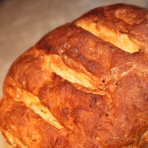 A loaf of mango cardamom raisin multigrain bread on a wooden work surface