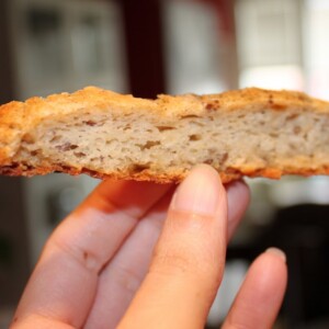 A slice of fennel and nigella seeds savory flat bread being held towards the camera