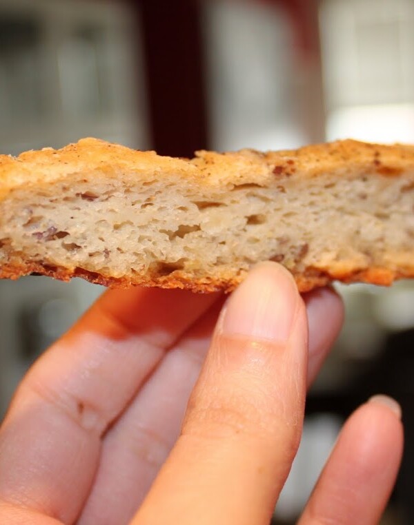 A slice of fennel and nigella seeds savory flat bread being held towards the camera