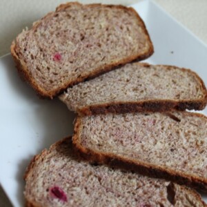 Slices of beet and strawberry wheat loaf spread out on a white plate