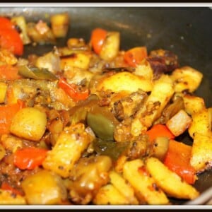 A closeup of baingan aloo cooking in a pan