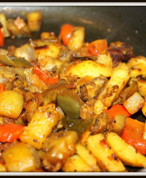 A closeup of baingan aloo cooking in a pan