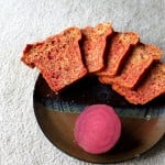 Slices of beet and blueberry mini loaf arranged on a plate with a slice of beet
