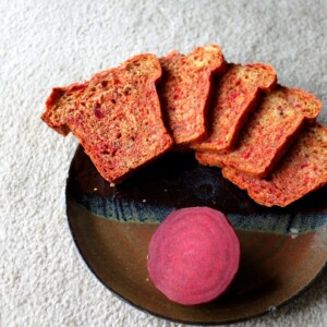 Slices of beet and blueberry mini loaf arranged on a plate with a slice of beet