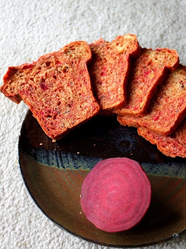 Slices of beet and blueberry mini loaf arranged on a plate with a slice of beet