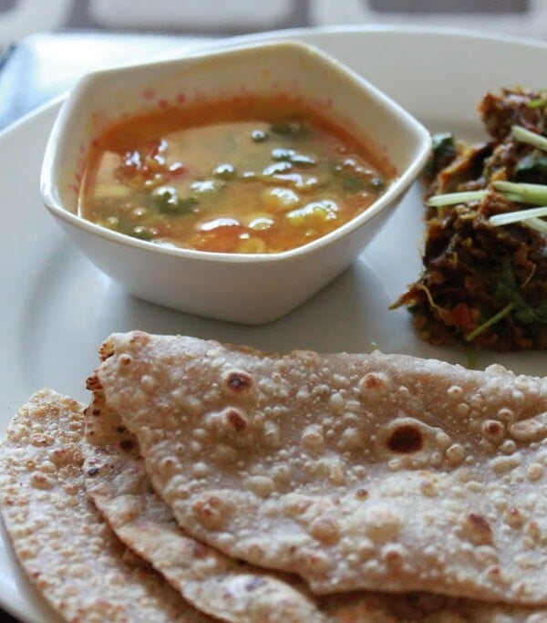 Baingan Bharta, sambhar, roti and papad sweved together on a white plate