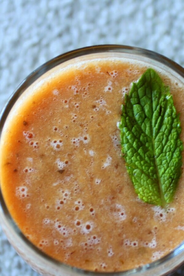 A top down shot of a mango strawberry mint cooler, garnished with a mint leaf