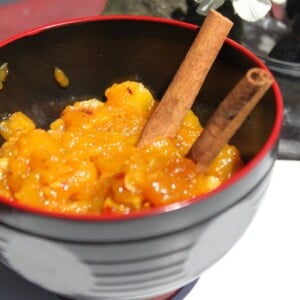 A bowl of mango chutney with two cinnamon sticks