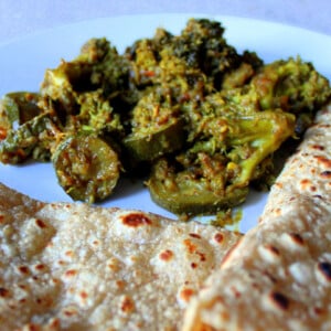 Broccoli and Zucchini in Onion and Pickle Spices served on a plate with roti