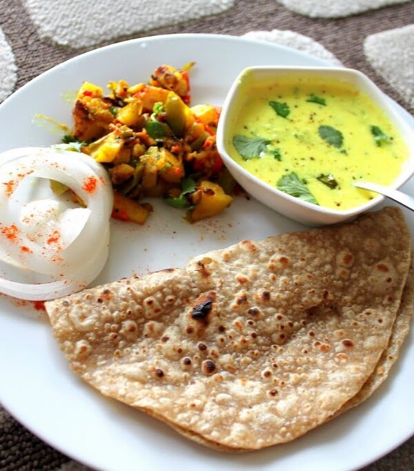 Tempered Cashew Yogurt, Spiced Potatoes and Bell Peppers with Indian Flat Bread served together on a white plate