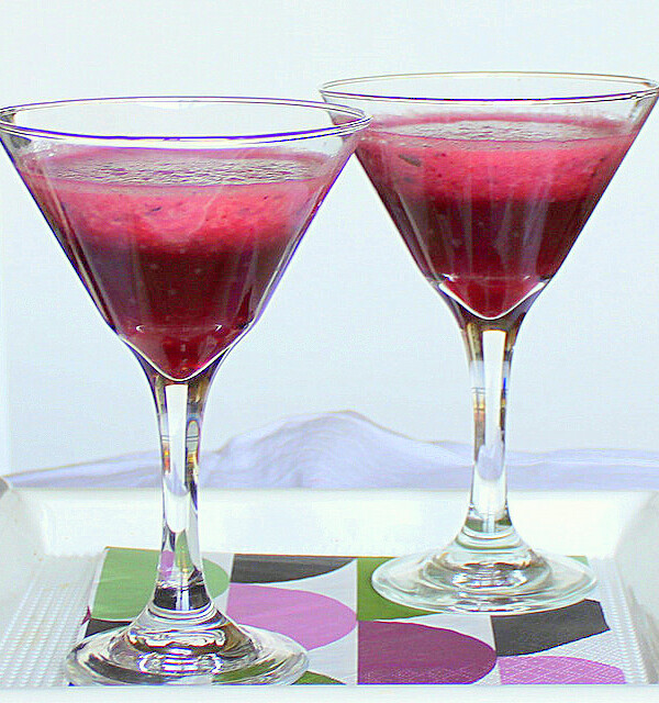 Two glasses of blueberry strawberry spiced cooler on a white background