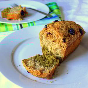 A carrot vanilla green tea layer cake on a white plate with the end of the loaf sliced off