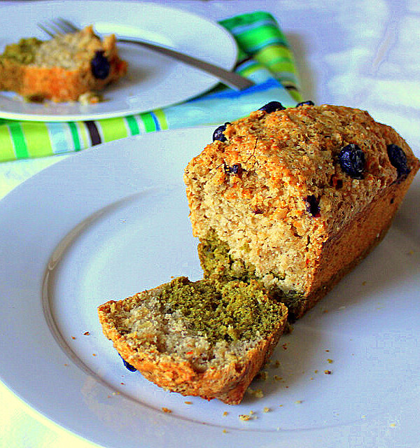 A carrot vanilla green tea layer cake on a white plate with the end of the loaf sliced off
