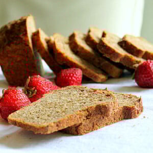 Slices of strawberry mango molasses loaf arranged with fresh strawberries