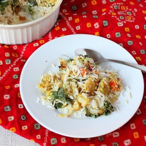 A white plate with layered rice and veggies on a red fabric