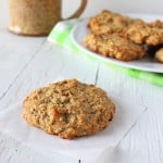 A quinoa raisin muffin cookie on a piece of parchment with a plate of cookies in the background
