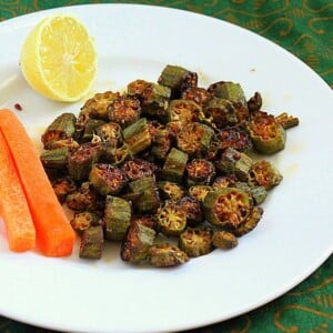 Crisp okra on a white plate werved with a lemon wedge and carrot sticks