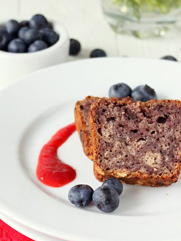 Two slices of blueberry Apple Whole Grain Cake served with fresh blueberries and a red sauce