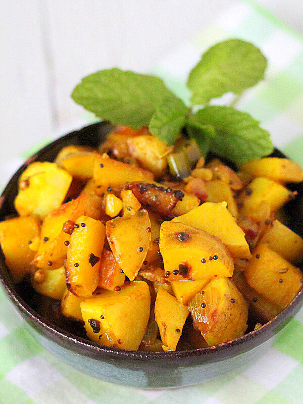 Potatoes with whole indian spices served in a bowl with cilantro garnish