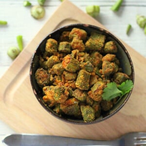 Bhindi Zunka in a dark bowl on a wooden chopping board