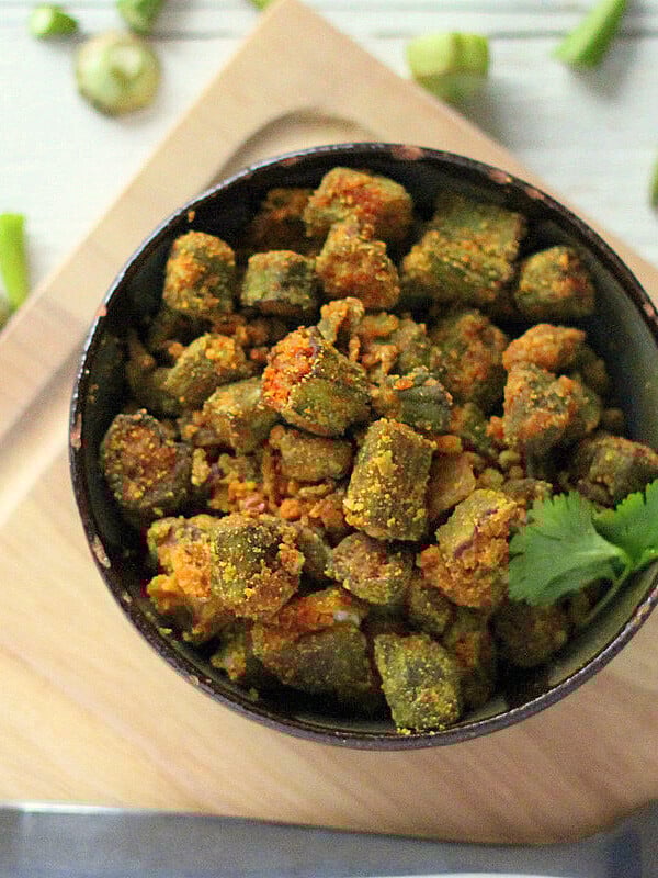 Bhindi Zunka in a dark bowl on a wooden chopping board