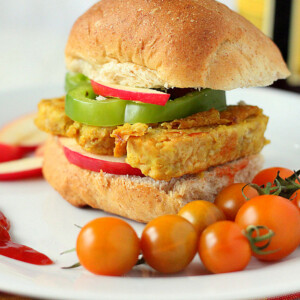 A tempeh frutter in a burger bun served with cherry tomatoes