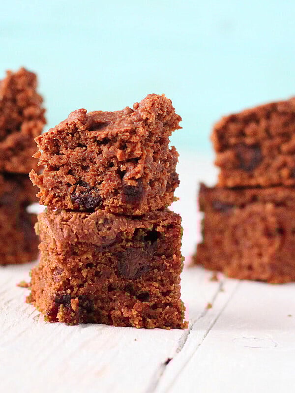 Vegan chocolate brownies stacked on a white wooden work surface
