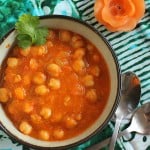 A bowl of vegan Chana Masala on a green cloth, garnished with cilantro