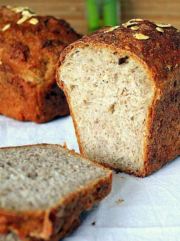 Two loaves of Sprouted Wheat Strawberry Bread cut in half on a work surface