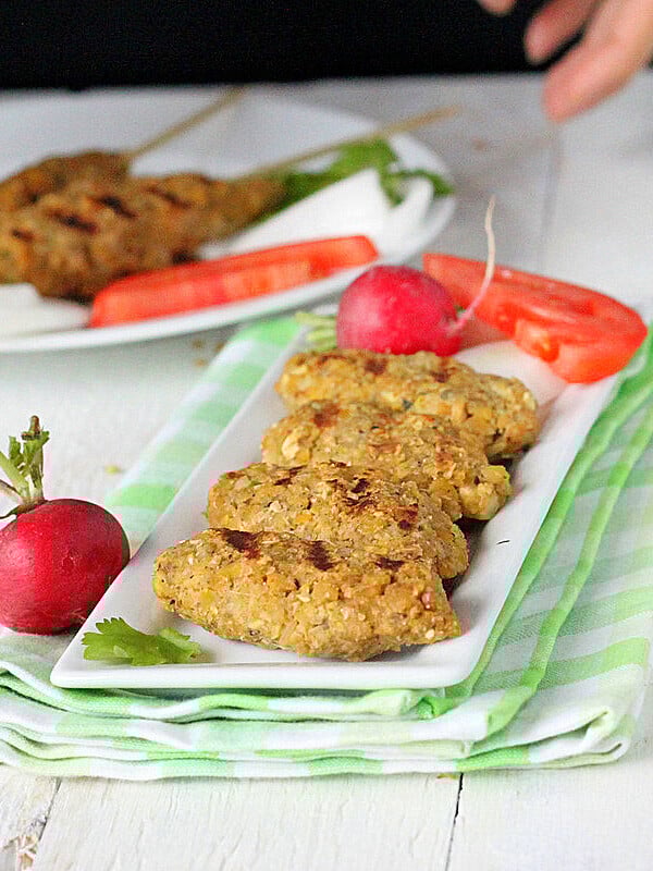 Tempeh Seekh Kebabs on a white serving plate with vegetable garnishes