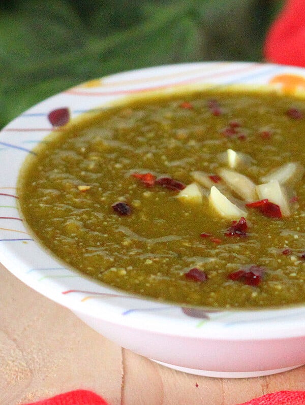 A bowl of creamy spinach soup on a wooden work top