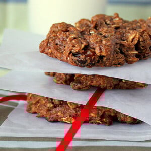 A stack of chocolate oatmeal raisin cookies separated by parchment paper