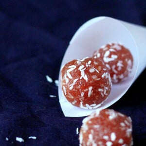 Pink coconut balls in a paper funnel on a dark background