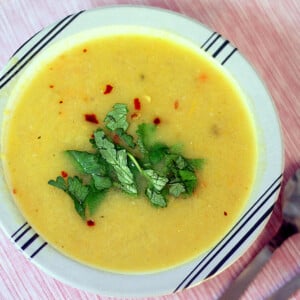 A bowl of carrot leek parsnip soup garnished with green leaves