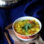 A yellow lentil stew in a bowl on a dark blue background
