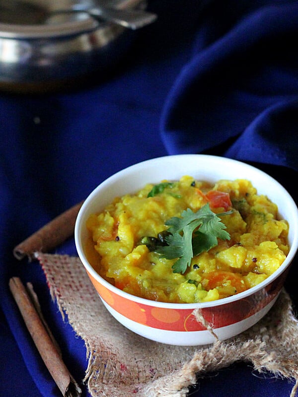 A yellow lentil stew in a bowl on a dark blue background