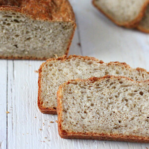 Pear Quinoa Chai spice Bread loaf with slices cut on a white wooden background.