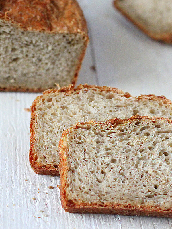 Pear Quinoa Chai spice Bread loaf with slices cut on a white wooden background.